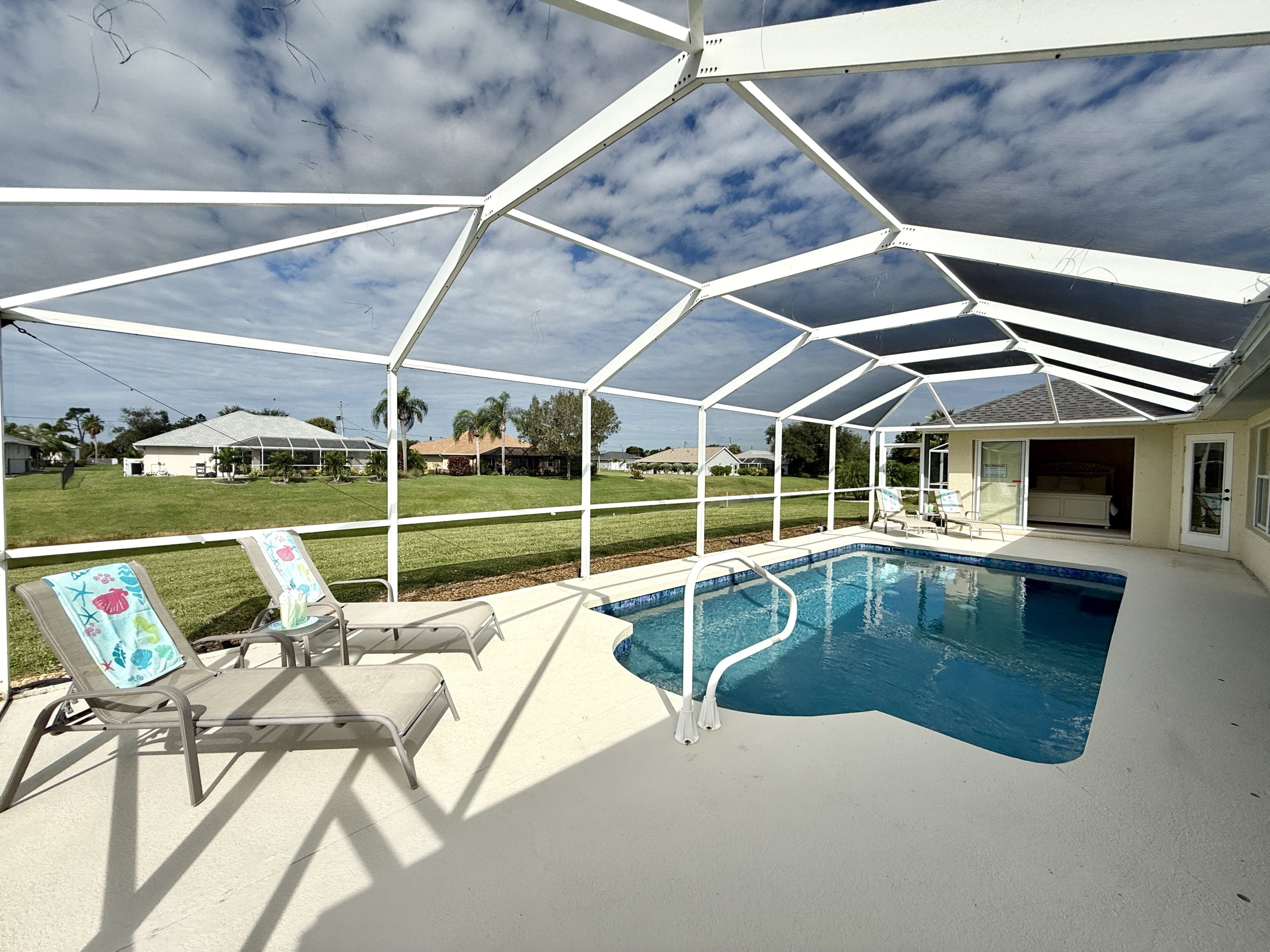 A covered outdoor swimming pool with lounge chairs and a view of a residential area.