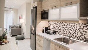 Eine moderne Küche mit Kühlschrank, Mikrowelle und Spüle. Es gibt einen Essbereich mit Tisch und Stühlen sowie ein Wohnzimmer mit Sofa und Lampe.