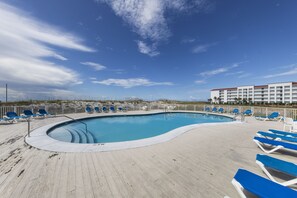 Relax by the resort pool surrounded by lounge chairs and a beautiful view.