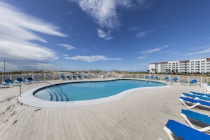 Relax by the resort pool surrounded by lounge chairs and a beautiful view.