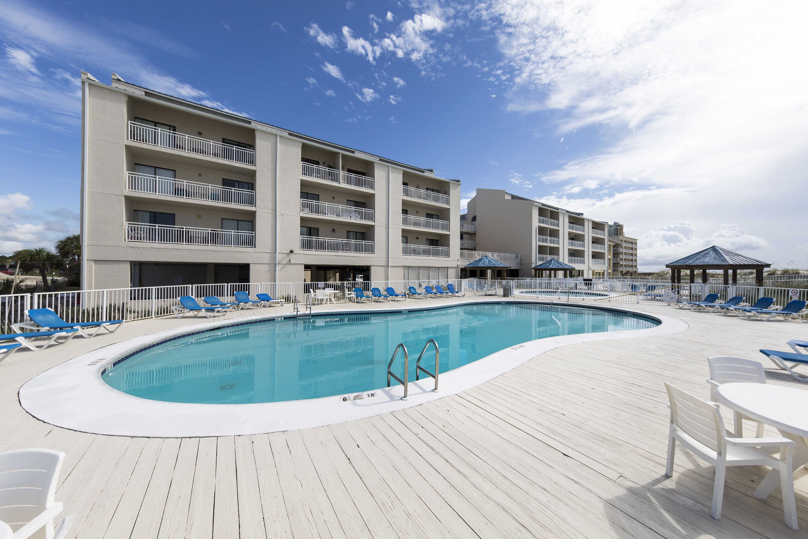 A hotel with a swimming pool, multiple balconies, and outdoor seating areas.