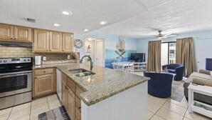 A modern kitchen with granite countertops, wooden cabinets, and a built-in oven. - NEWLY RENOVATED CONDO- ON BEACH (Orange Beach)