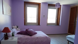 A bedroom with a bed, a bedside table with a lamp, a small plant, and a window. - Gîte for 10 people (Prémanon)