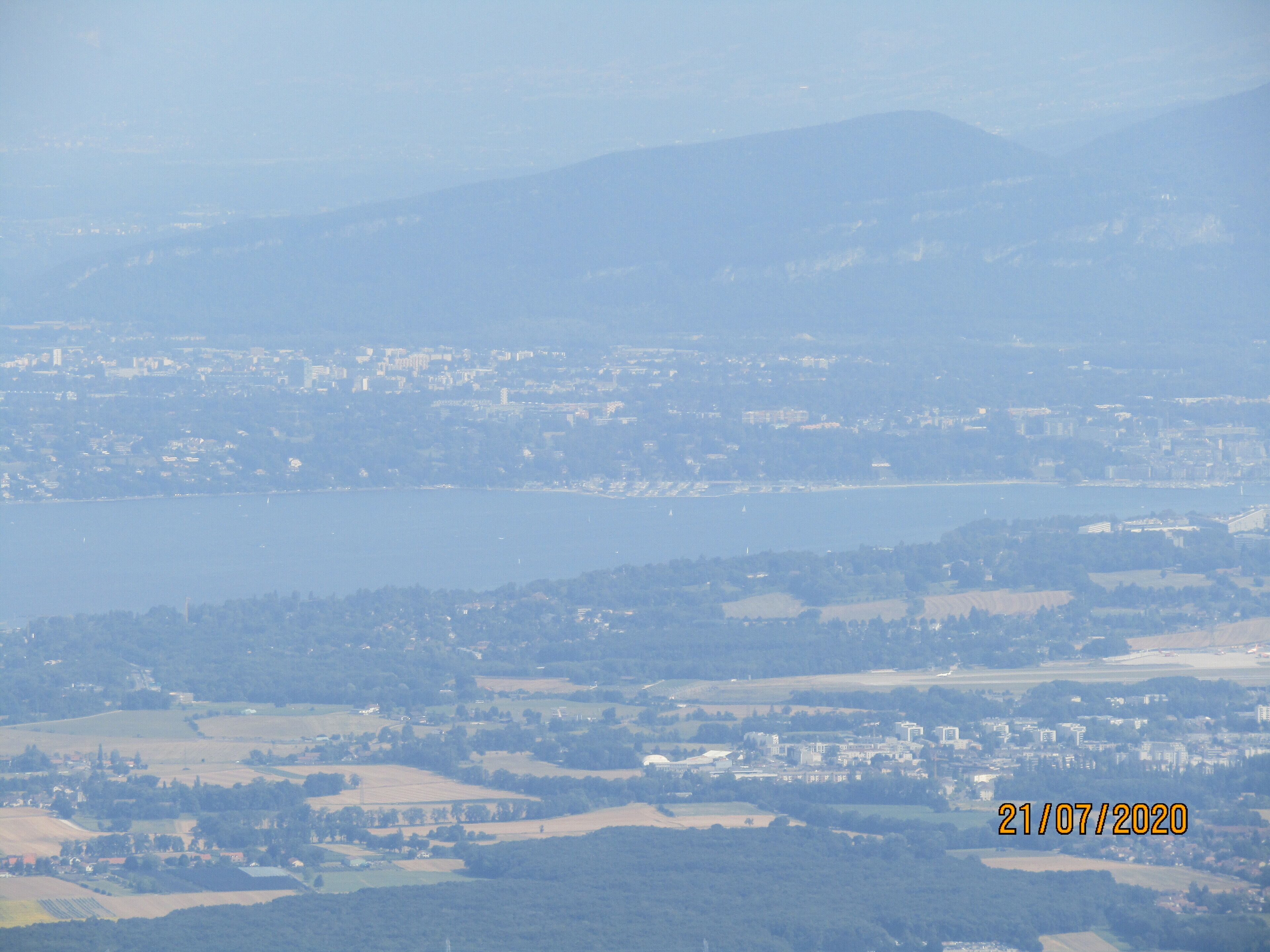Une vue panoramique d’une ville côtière, avec une vaste étendue d’eau, des zones urbaines et des collines environnantes.