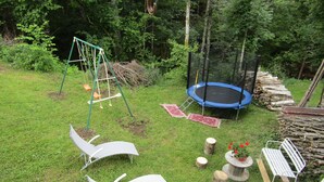 A backyard with a trampoline, swing set, and two lounge chairs. - Gîte for 10 people (Prémanon)