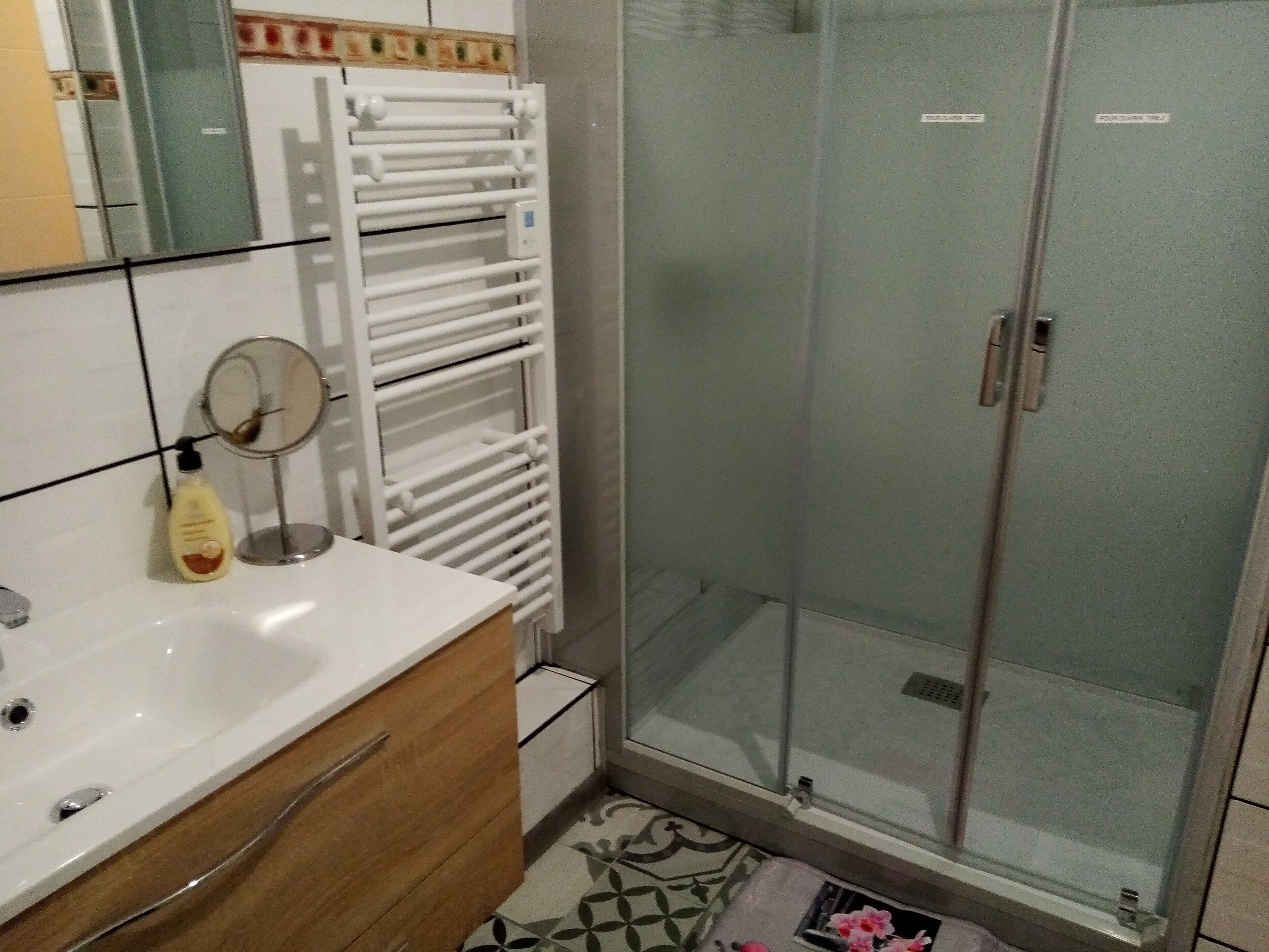 A bathroom with a white sink, a mirror, a towel rack, and a glass shower enclosure.