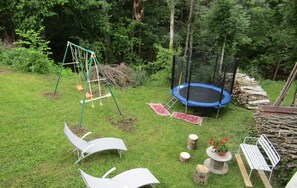A backyard with a trampoline, swing set, and two lounge chairs. - Gîte for 10 people (Prémanon)