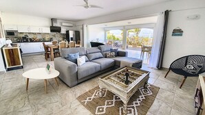 Una sala de estar moderna con un sofá gris, una mesa de centro y un área de comedor al fondo.