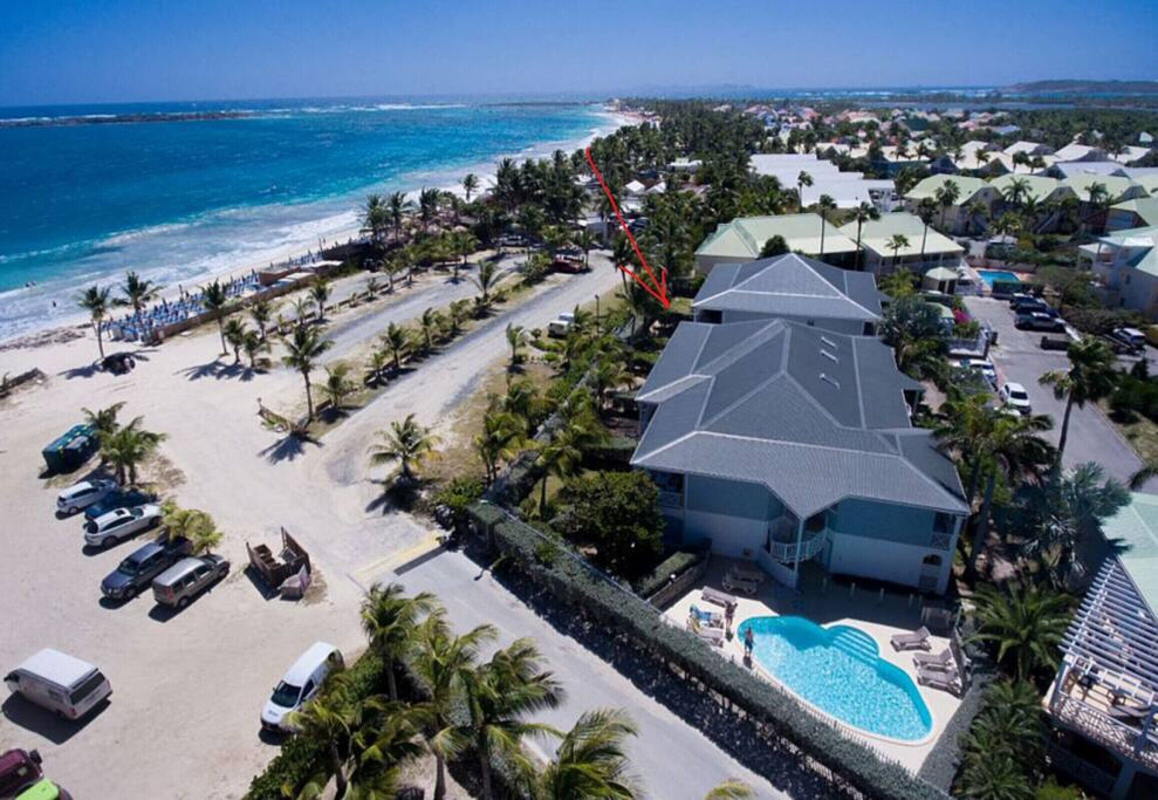 An aerial view of a resort with a pool, beach, and ocean.
