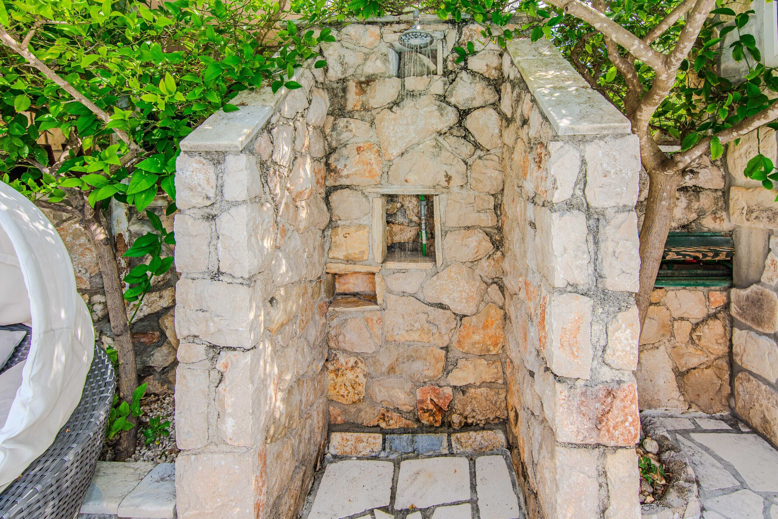 A stone-built structure with a small opening, surrounded by greenery.