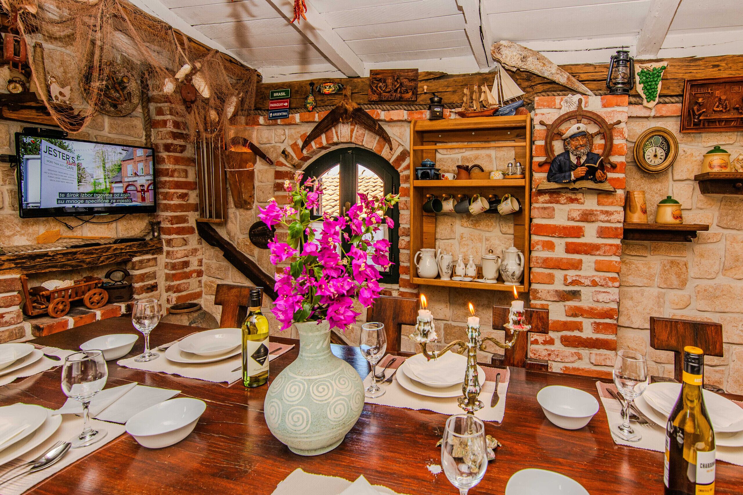A dining area with a brick wall, a television, and a table set for a meal.
