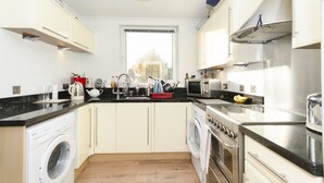 Una cocina compacta equipada con lavadora, horno, microondas y pileta.