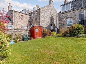A stone building with a red shed in the yard, surrounded by well-maintained grass and shrubs. - City Apartment With Rural Charm (Aberdeen)