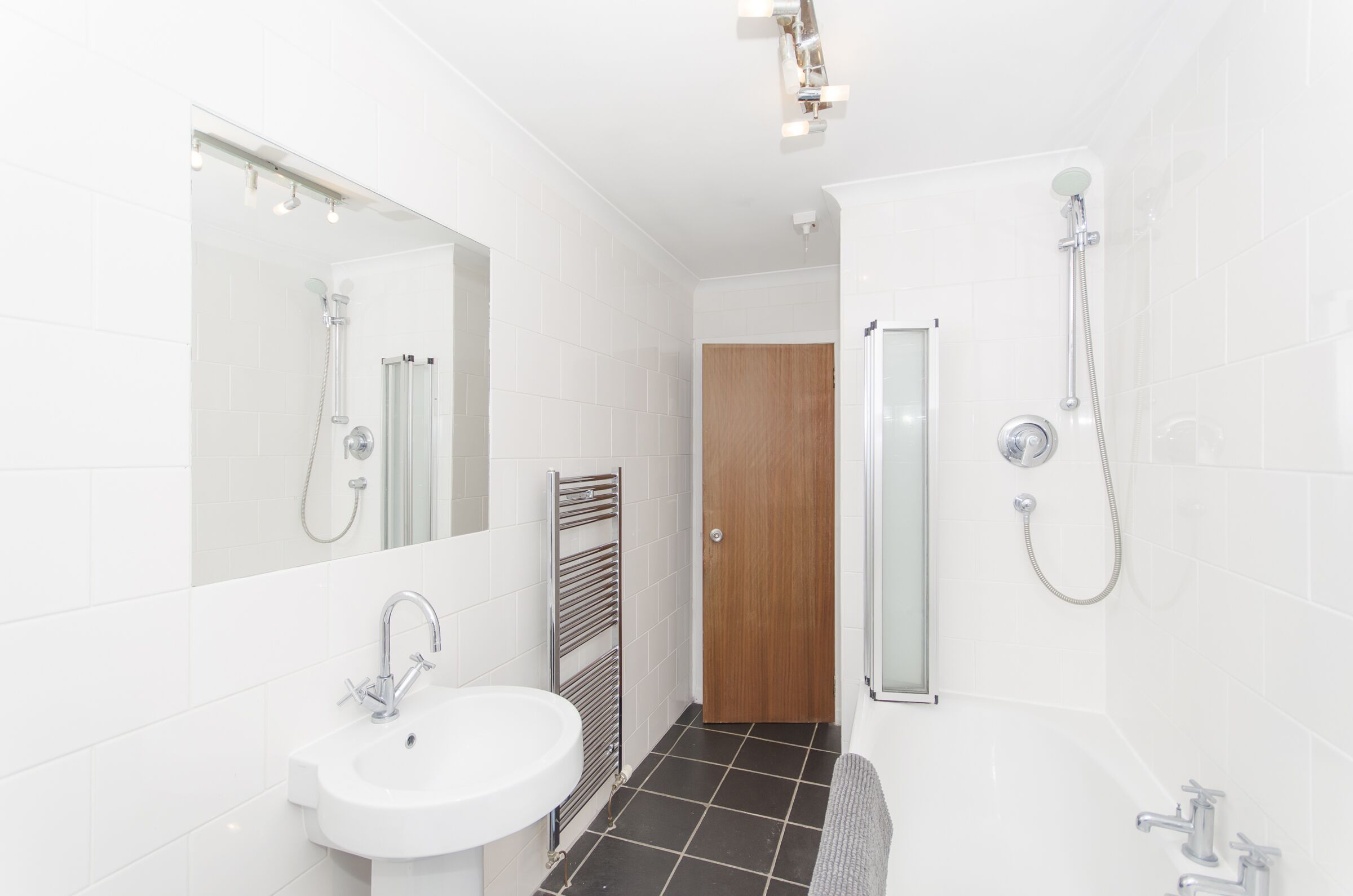 A modern bathroom with a white sink, mirror, and shower.