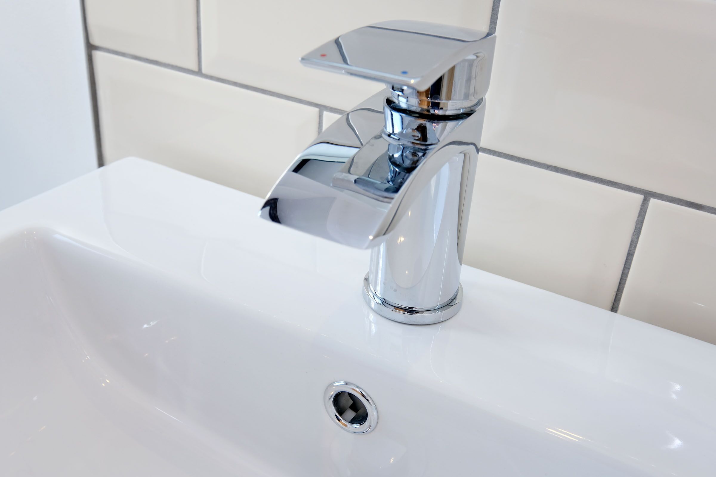 Ein weißes Waschbecken mit einem chromfarbenen Wasserhahn und Abfluss.