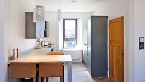 A modern kitchen with a dining area, built-in appliances, and a view through a window. - Ben Shea Smart Home (Keith)