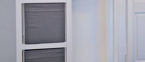 Un armario blanco con cojines grises y una puerta blanca al fondo.
