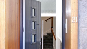 A wooden door with a metal handle, a number '21' on the wall, and a staircase with carpeted steps. - Ben Shea Smart Home (Keith)
