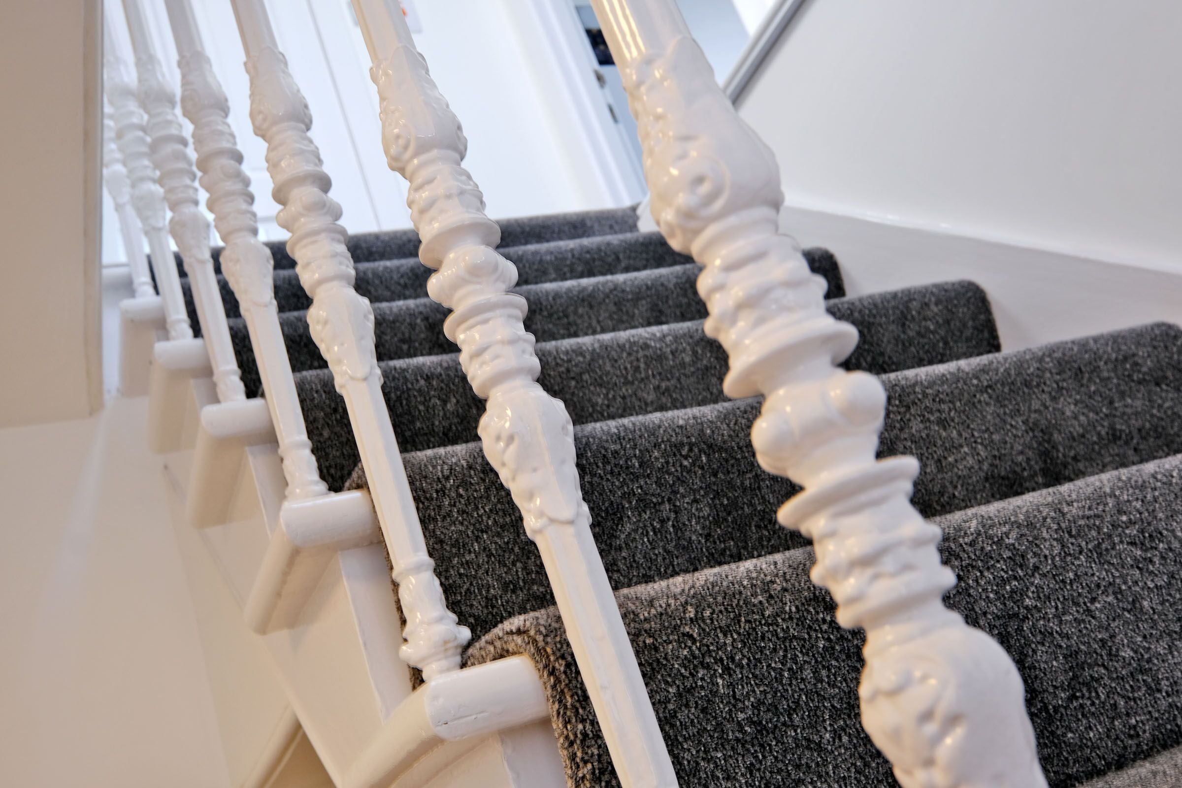 A staircase with white balusters and dark carpeted steps.