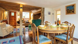 A dining area with a round wooden table, blue cushioned chairs, and a brick wall in the background. - 4 bedroom accommodation in Dallington, near Heathfield (Dallington, near Heathfield)
