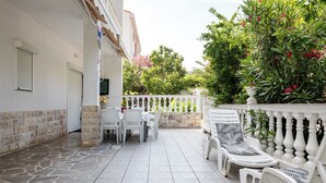 A patio with white chairs and a table, a white fence, and a stone wall. - Rab Oasis Retreat - 3 Bedroom Apartment (Rab)