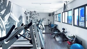 A gym with cardio machines, weightlifting equipment, and a large exercise ball. - Apartamento Conforto - Itaim Bibi (São Paulo)