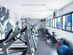 A gym with cardio machines, weightlifting equipment, and a large exercise ball.