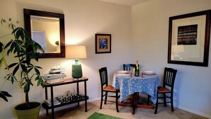 A dining area with a table set for two, a green potted plant, a chessboard, and a framed picture on the wall. - Cozy Condo Near City Dock - Your Perfect Annapolis Getaway! (Annapolis)