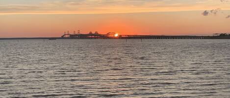 A sunset over a calm body of water with a pier extending into the water.