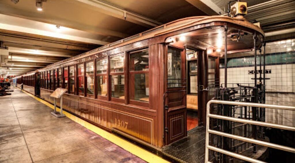 A vintage train car with wooden paneling and a metal railing at the platform.
