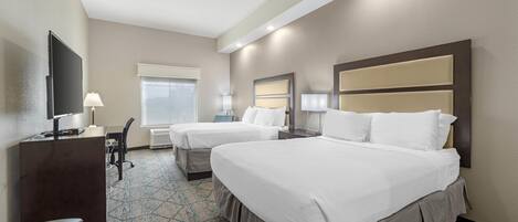 A hotel room with two beds, a desk, a chair, a TV, and a window.