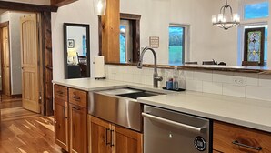 A modern kitchen with wooden beams, stainless steel appliances, and a large window. - Custom Finger Lakes home near Ithaca with hot tub  (Newfield)