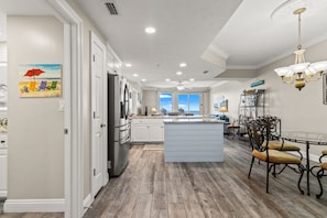 A kitchen with white cabinets, a central island, and a dining area with chairs.