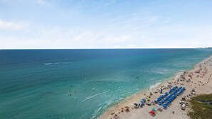 A beach with clear waters, a sandy shore, and numerous umbrellas. - Treasure Island 1611 (Panama City Beach)