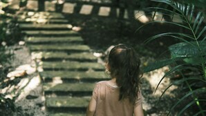 Un nen caminant per una escala de pedra envoltada de verdura.