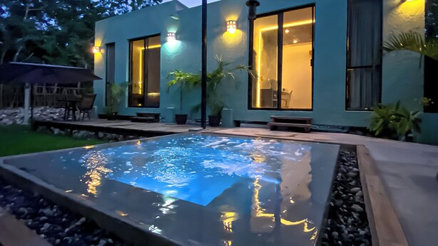 Una casa moderna amb piscina, finestres grans i il·luminació exterior.