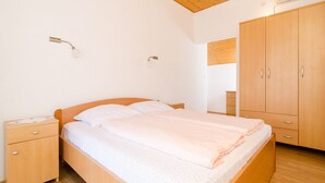 A bedroom with a wooden bed, nightstands, a wardrobe, and a ceiling with wooden beams. - Holiday Home Maćus-One Bedroom Apartment with Balcony (Kolocep)