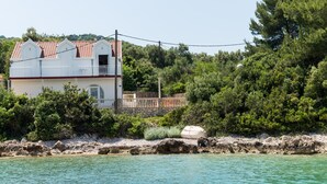 A coastal house with a red-tiled roof, a balcony, and a stone wall. - Holiday Home Maćus-One Bedroom Apartment with Balcony (Kolocep)