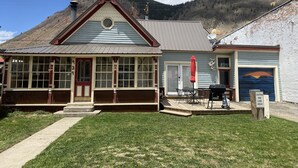 A building with a porch, a garage, and a mountain backdrop.