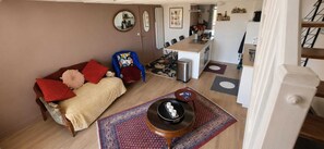 A compact living space with a sofa, a small round table, a kitchen area, and a dining table. - Idéal Vacances, vue Mer, Accès Direct à la Plage (Gâvres)