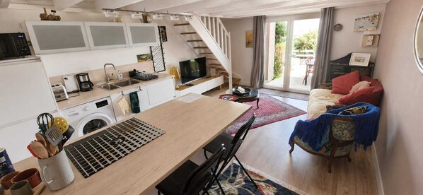 A compact living space with a kitchen, dining area, and seating area. - Idéal Vacances, vue Mer, Accès Direct à la Plage (Gâvres)
