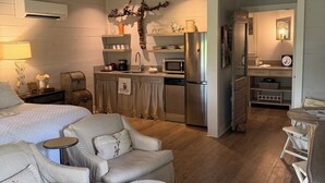 A modern living room with a sofa, ottoman, and a dining area with a table and chairs. - Cozy and comfortable one bedroom with kitchen and with pasture view. (Burton)