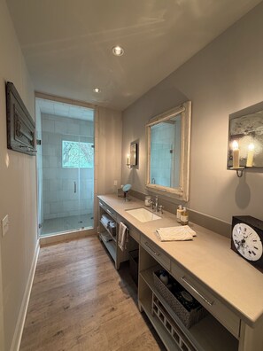 A bathroom with two sinks, a mirror, a clock, and a shower area.