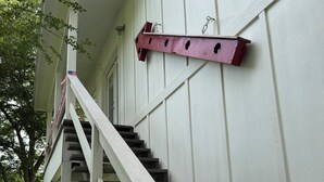 A staircase with a white handrail and steps leading to a porch area. - Cozy and comfortable one bedroom with kitchen and with pasture view. (Burton)