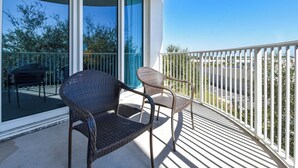 A balcony with two wicker chairs and a table, overlooking a residential area with trees and houses. - Family-Friendly Condo w/ Fun Amenities & Onsite Restaurant in Central Destin! 🌊 (Destin)