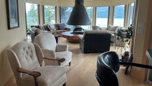 A spacious living room with a fireplace, large windows, and a view of the outdoors.