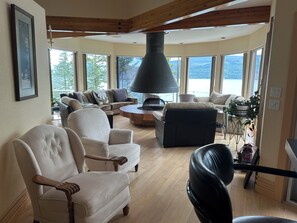 A spacious living room with a fireplace, large windows, and a view of the outdoors.