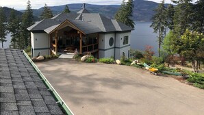 A house with a porch, a chimney, and a view of a lake and mountains.