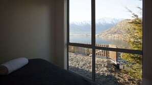 A room with a large window offering a view of a lake and mountains.