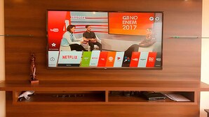 A television mounted on a wooden wall displaying a TV show with a red and white background. - Nice Apartment Malecon Balta Miraflores (Lima)